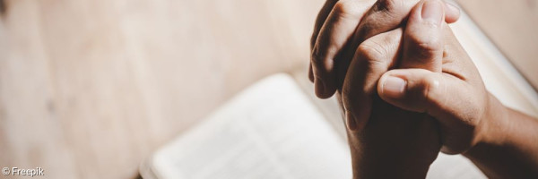 Betende Hände über einem Buch